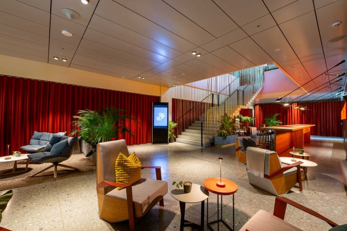 Lounge im Park Side Social Frankfurt mit Sesseln, rotem Vorhang und atmosphärischer Beleuchtung